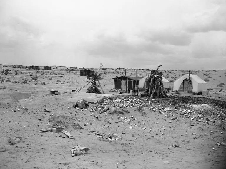 Tents and small cabins in the foreground of a desert landscape