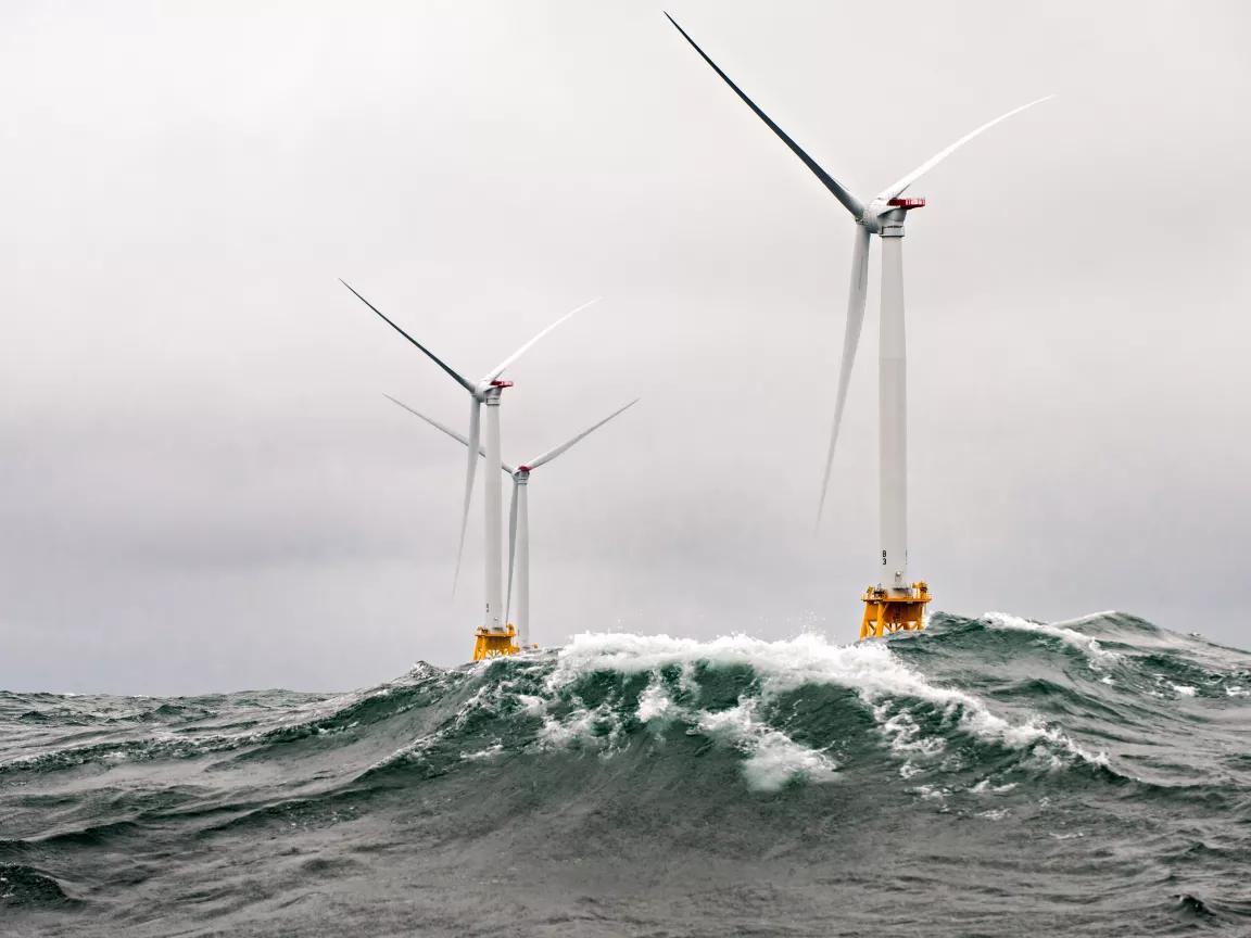 Three offshore wind turbines surrounded by waves, off the coast of Rhode Island