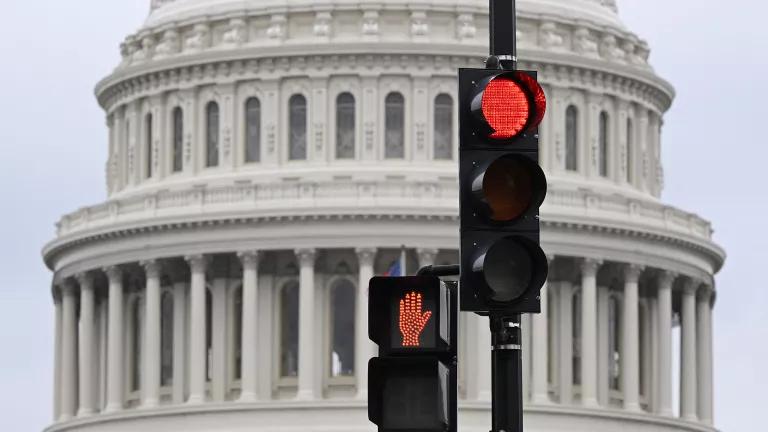 A traffic stoplight and pedestrian stoplight, both on red, in front of the U.S. Capitol building in Washington, D.C.