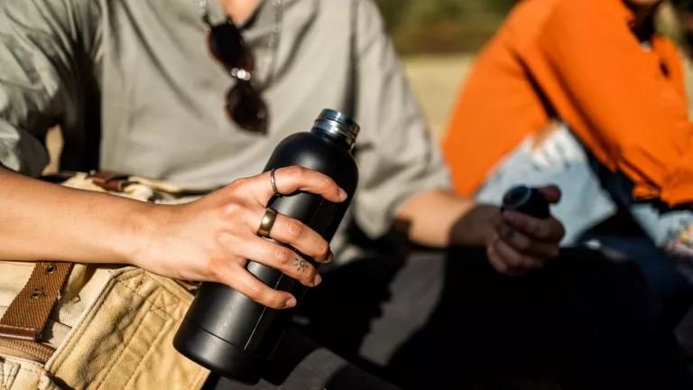 A close-up view of a person holding a reusable water bottle