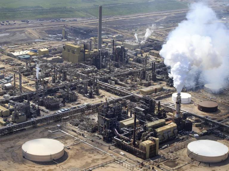 An aerial view of an industrial facility with tall smokestacks and holding tanks