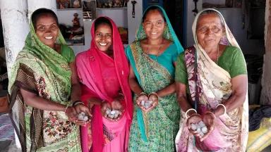 Four women in holding handfuls of harvested salt in the village of Kuda, Gujarat, India