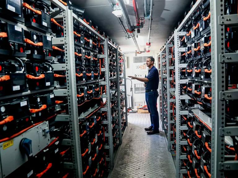 A man standing in a storage room shelved with lithium-ion battery packs