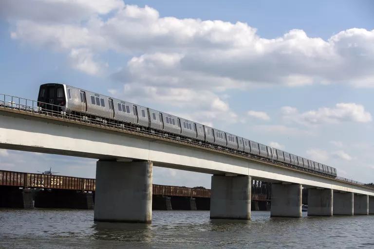 A passnger train crosses over a bridge on a river
