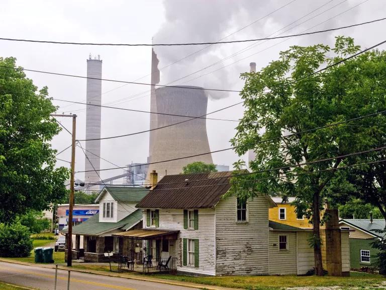 A residential neighborhood with a coal-fired power plant spewing smoke in the background