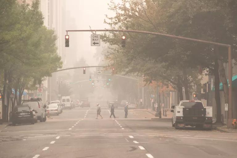 A thick smog hangs over a mostly-deserted city street.