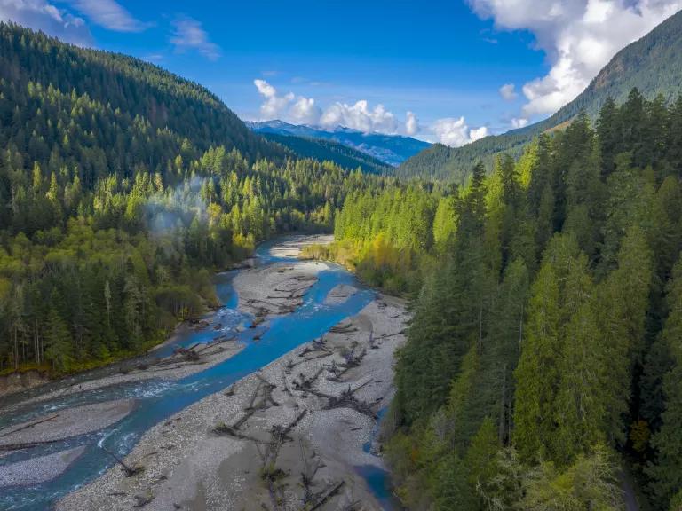 An aerial view of the Noosack River surrounded by lush green forests in Glacier, Washington