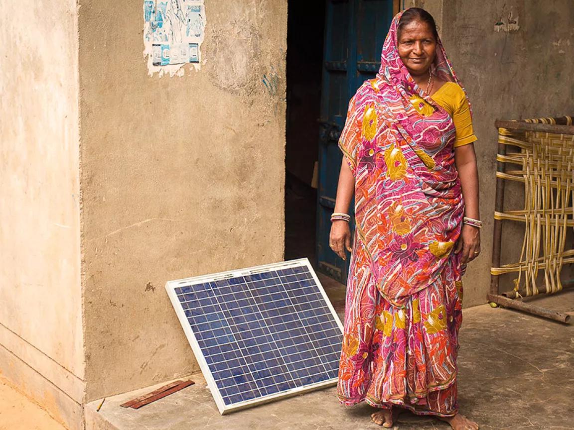 Salt farmer Bhavnaben Koli, a member of the Self Employed Women's Association, standing beside a solar panel outside her home in the village of Kuda, Gujarat, India