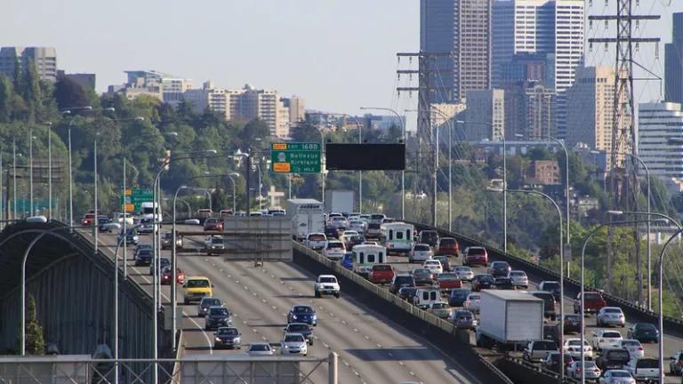 Cars and trucks sit in a traffic jam in one direction on a highway overpass.